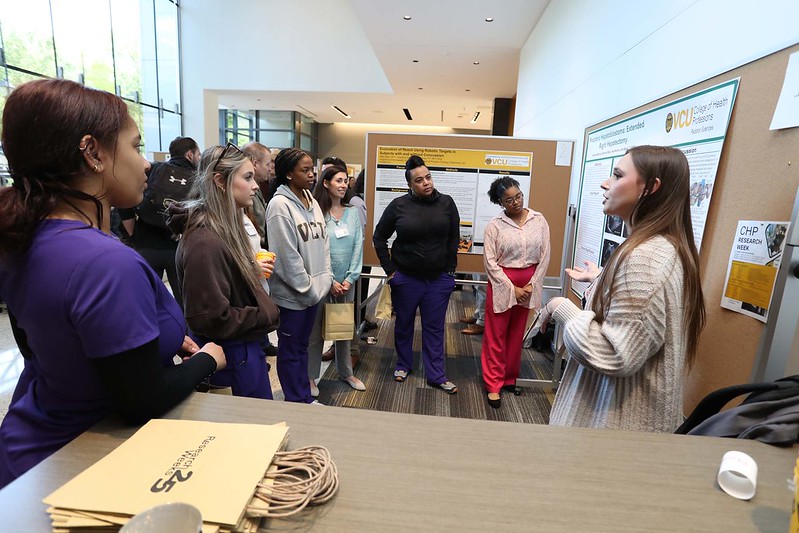 Student presenting poster to a crowd at research week 2025