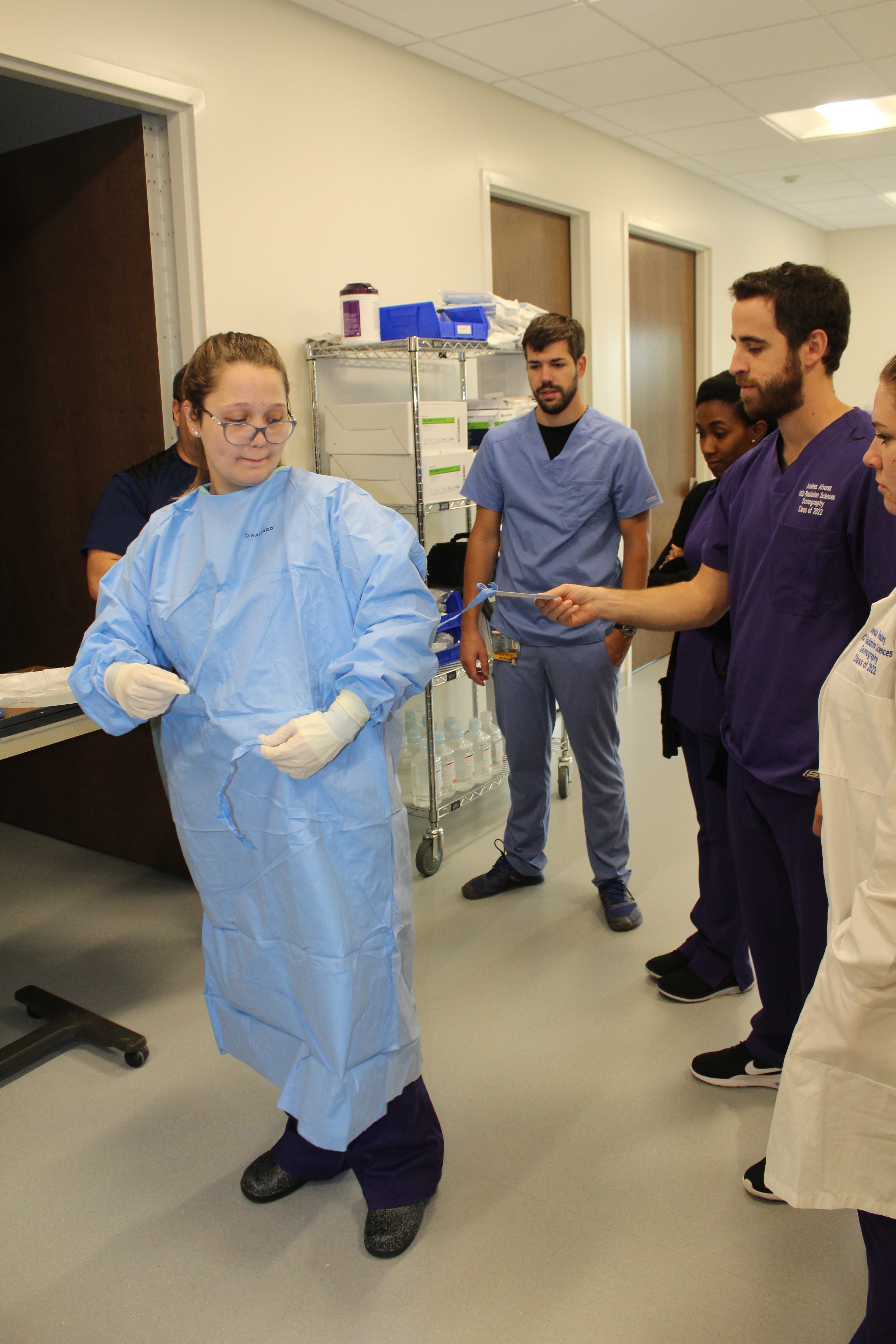 Students gather to watch how to put on a surgical gown