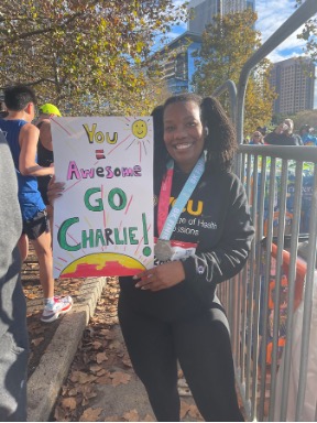 Charlie Downing holding a sign that says You equals Awesome Go Charlie