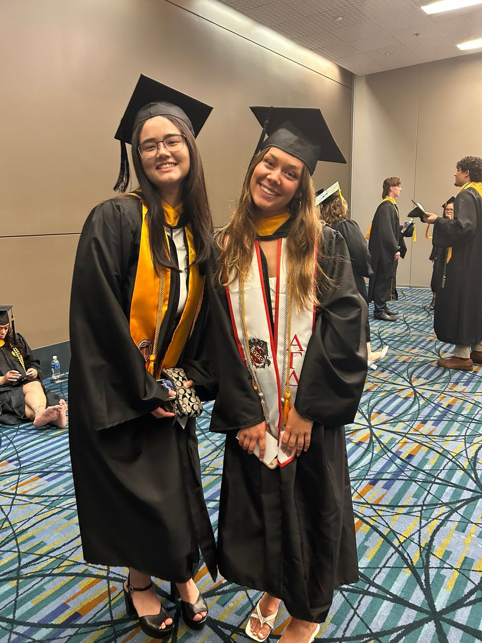 Two radiography students posing for picture in cap and gown