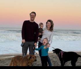 Bridget Winkler and family and dogs standing on a beach at sunset